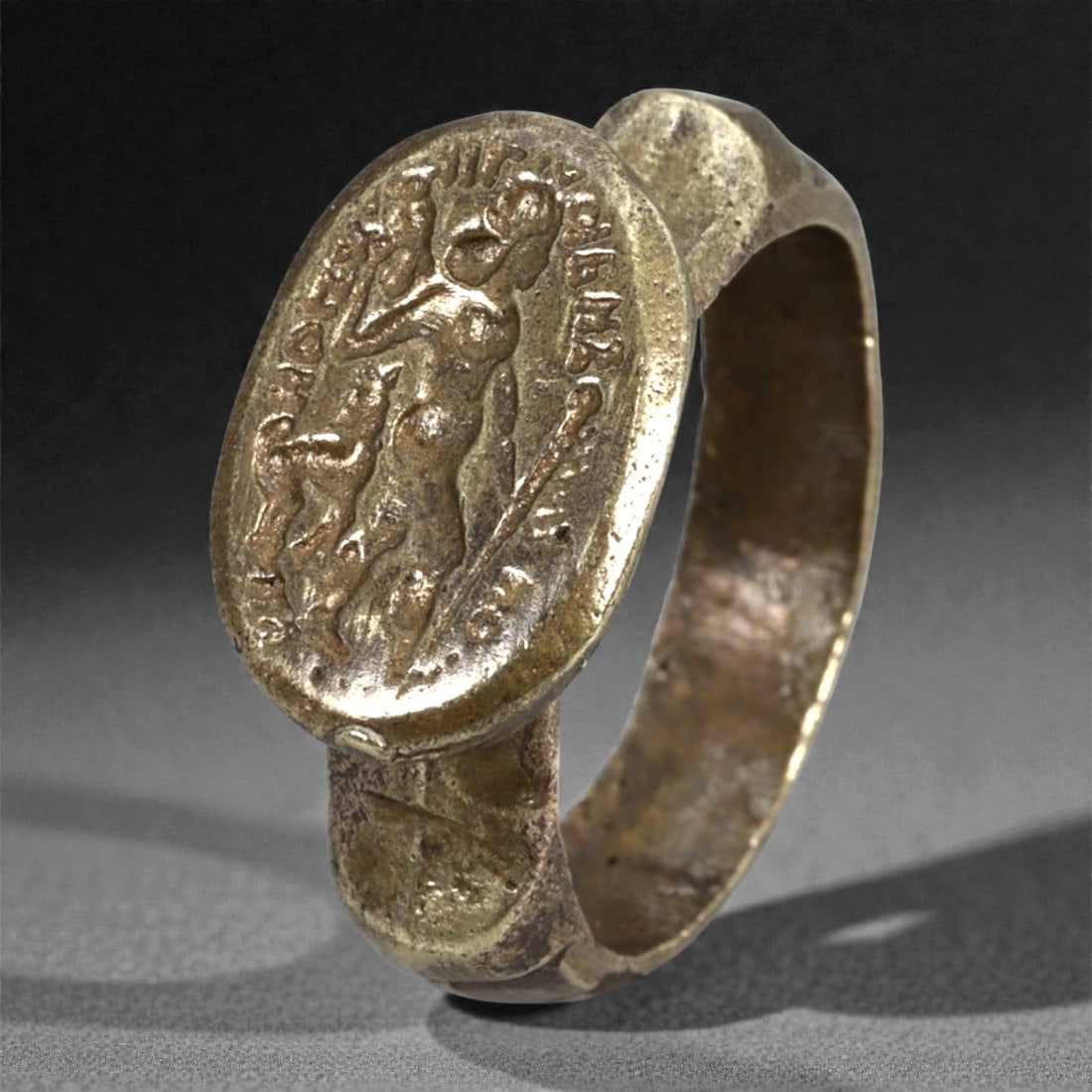 Antique Qajar Era Copper Alloy Ring with Heroic Figure Intaglio, c. 19th-20th Century, 8g, 86N: This antique copper alloy ring originates from the Qajar period of Persia, a time when classical iconography was reinterpreted through local artistic and symbolic traditions. The oval bezel is cast wi