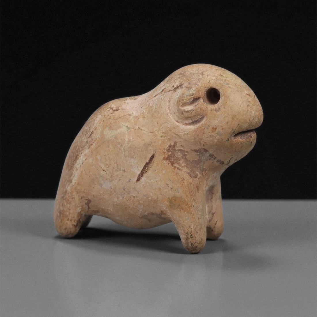 A Near Eastern Stone Zoomorphic Figurine, 3rd-2nd Millennium BCE, 32LA: Carved from light brown stone with scattered surface accretions, the figure represents a compact quadruped with a rounded body and short legs. The head is slightly raised, with a drilled circular eye,