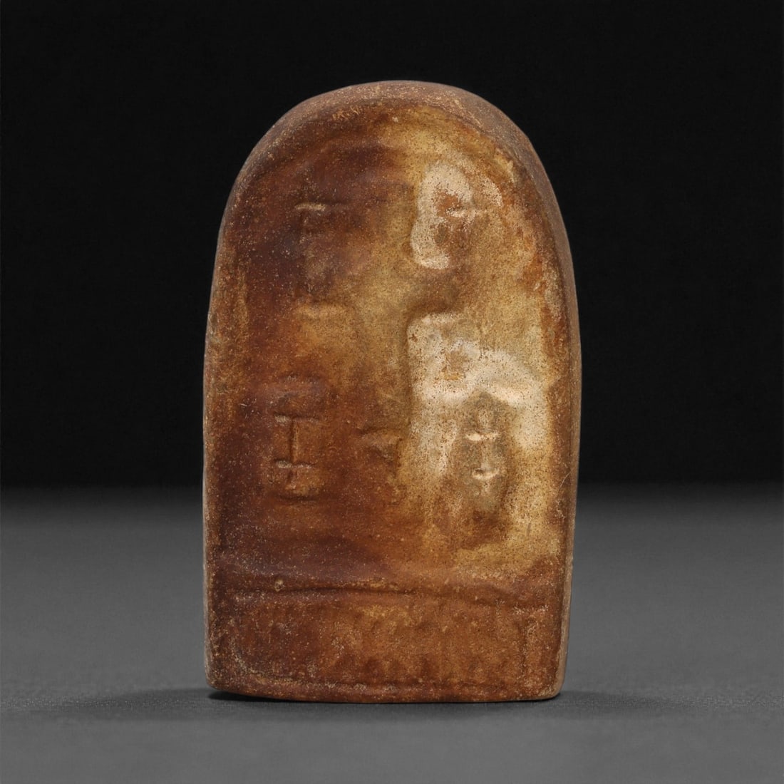 A Late Antique Stone Christian Stela, 4th-7th Century CE, 59LA: Carved from a light brown stone with a rounded upper edge, the surface bears low-relief elements including a linear vertical figure and adjacent schematic forms. The lower register displays a shallow 