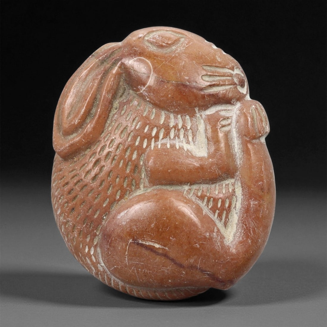 Ancient Medieval Persian Stone Medallion of a Hare, c. 12th-13th Century CE, 5.6cm, 8ER: This charming carved stone medallion, depicting a hare in repose, dates to the 12th-13th century CE during the Seljuk period of medieval Persia. Crafted from warm reddish-brown stone with pale incised