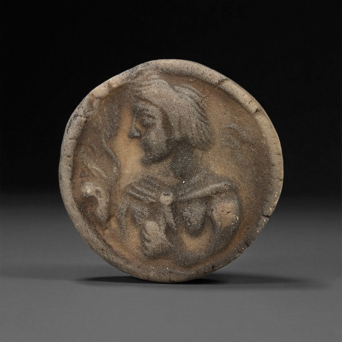 Ancient Parthian Clay Portrait Seal Stamp, c. 1st-3rd Century CE 4cm, 30ES: This ancient Parthian clay seal stamp, measuring 4 cm, offers a compelling glimpse into the artistic and administrative world of the Parthian Empire. Its circular form bears a raised portrait of a fig