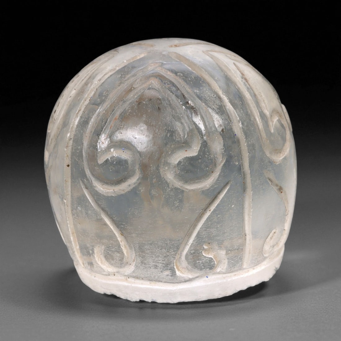 A Medieval Coptic Egyptian Scroll Design Glass Chess Piece, c. 10th-12th Century CE, 2.9cm, 4ER: Carved from translucent pale glass with a smooth domed form, this elegant piece dates to the Coptic Egyptian period of the Medieval era, circa 10th-12th century CE. Its symmetrical, scroll-like motifs