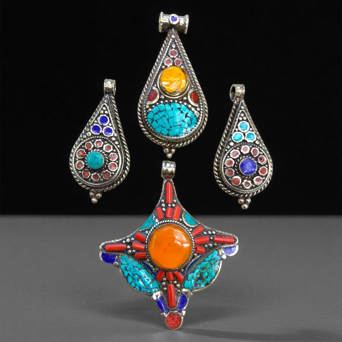 Vintage Himalayan Tribal Silver and Stone Inlay Pendants, c. 20th Century, 139g, 84DD: This striking ensemble of four pendants embodies the vivid artistry and spiritual symbolism of Himalayan tribal jewelry from the 20th century. Crafted in the highland regions of Nepal and Tibet, these
