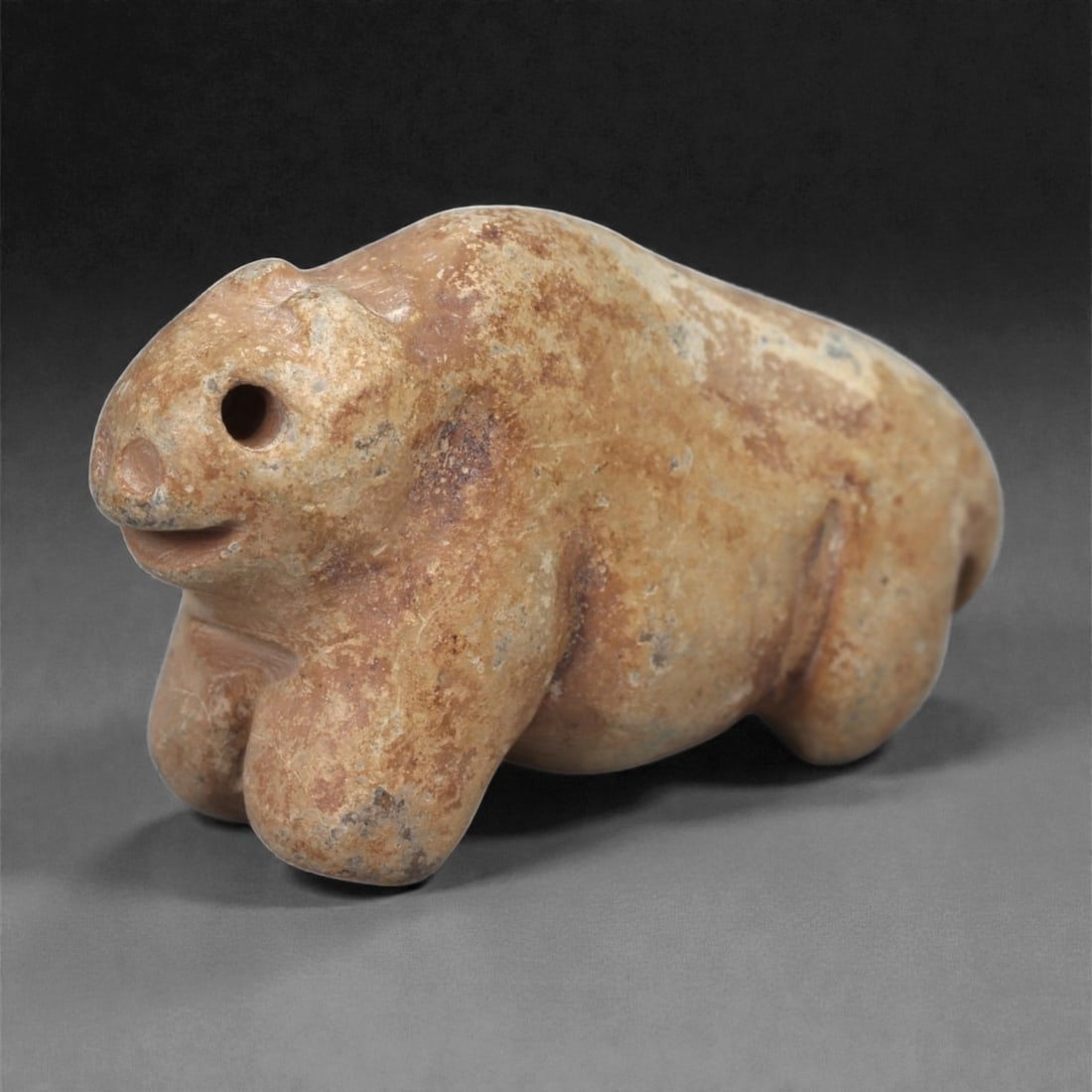 A Near Eastern Stone Zoomorphic Figurine, 3rd-2nd Millennium BCE, 46LB: Carved from light brown stone with surface accretions, the figure depicts a quadruped with a rounded body and short limbs. The head is modeled with a drilled circular eye, a small projecting snout, an
