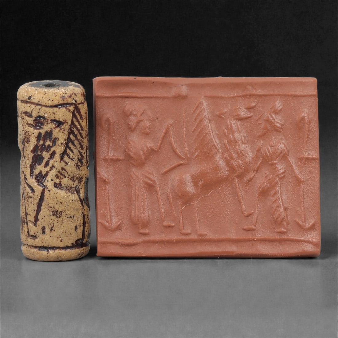 A Near Eastern Stone Cylinder Seal, 3rd Millennium BCE, 3.8cm, 34LH: Carved from stone with darker surface mottling, the cylindrical seal bears a continuous engraved scene. The carving is executed in shallow linear grooves typical of Early Bronze Age glyptic traditions