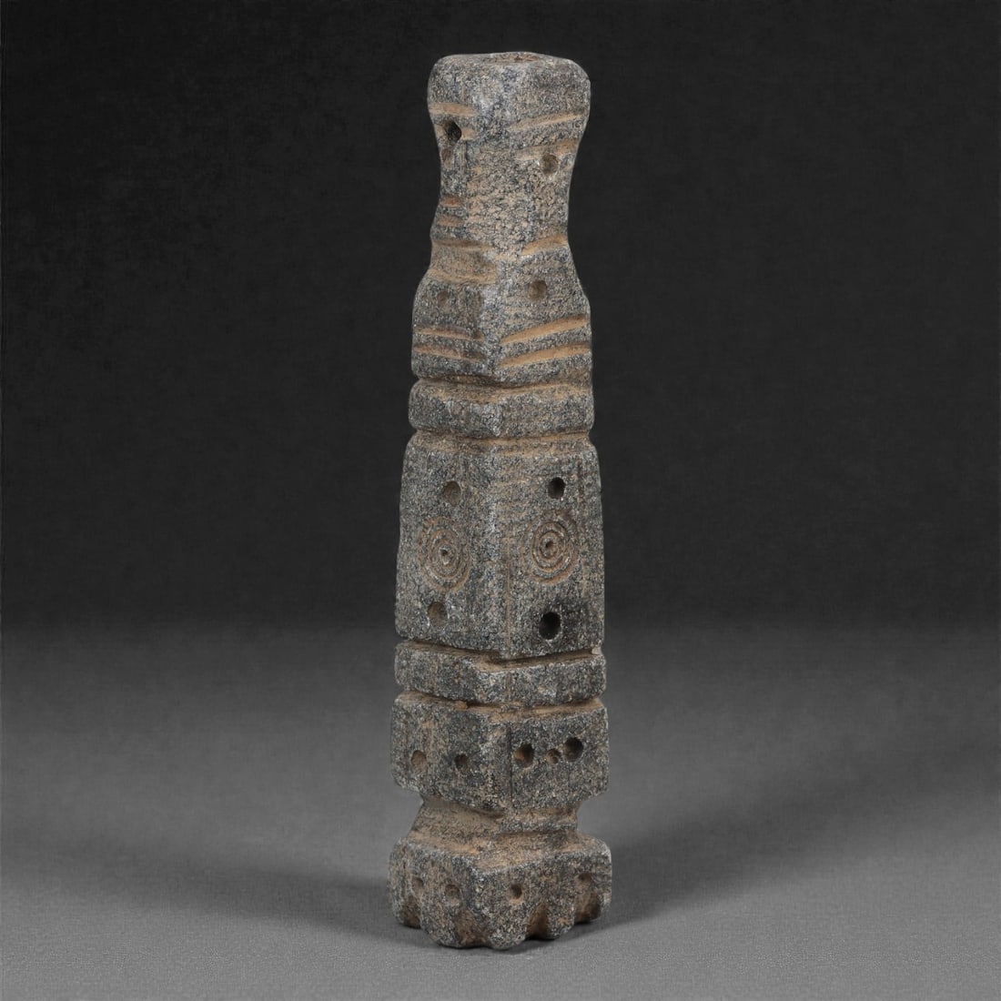 A Syro-Hittite Schist Columnar Amulet, Iron Age II, Circa 10th-8th Century BCE, 1LK: Carved from dark grey schist, the object is formed as a tall columnar amulet composed of stacked geometric segments, each delineated by horizontal grooves. The lower sections are square in plan and be