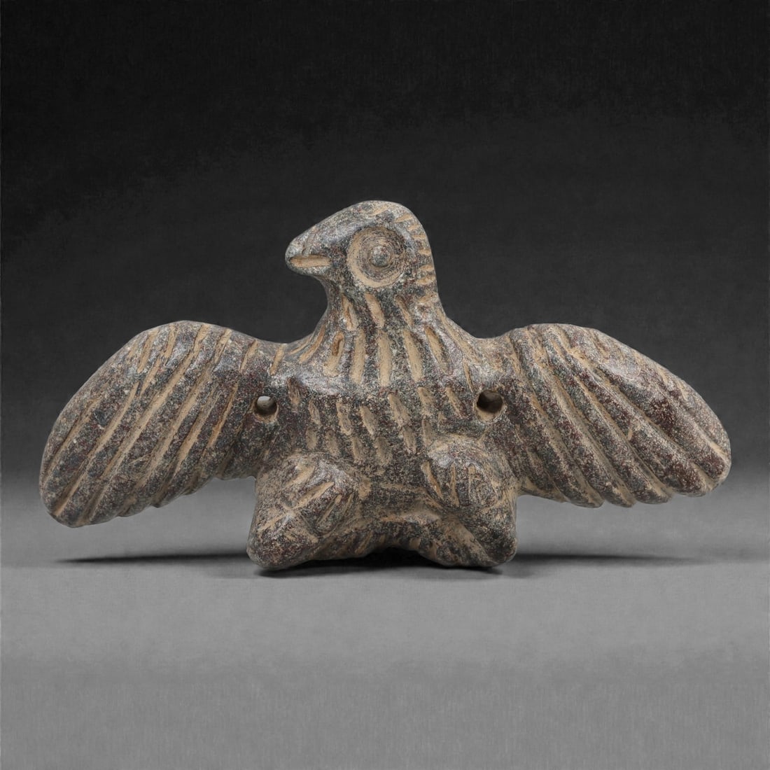 A Syro-Anatolian Schist Vulture Figure, Early to Mid-2nd Millennium BCE, 73LJ: Carved from grey schist, the figure depicts a vulture with fully outstretched wings, each articulated by long parallel incisions indicating the primary feathers. The body is compact, with short legs t