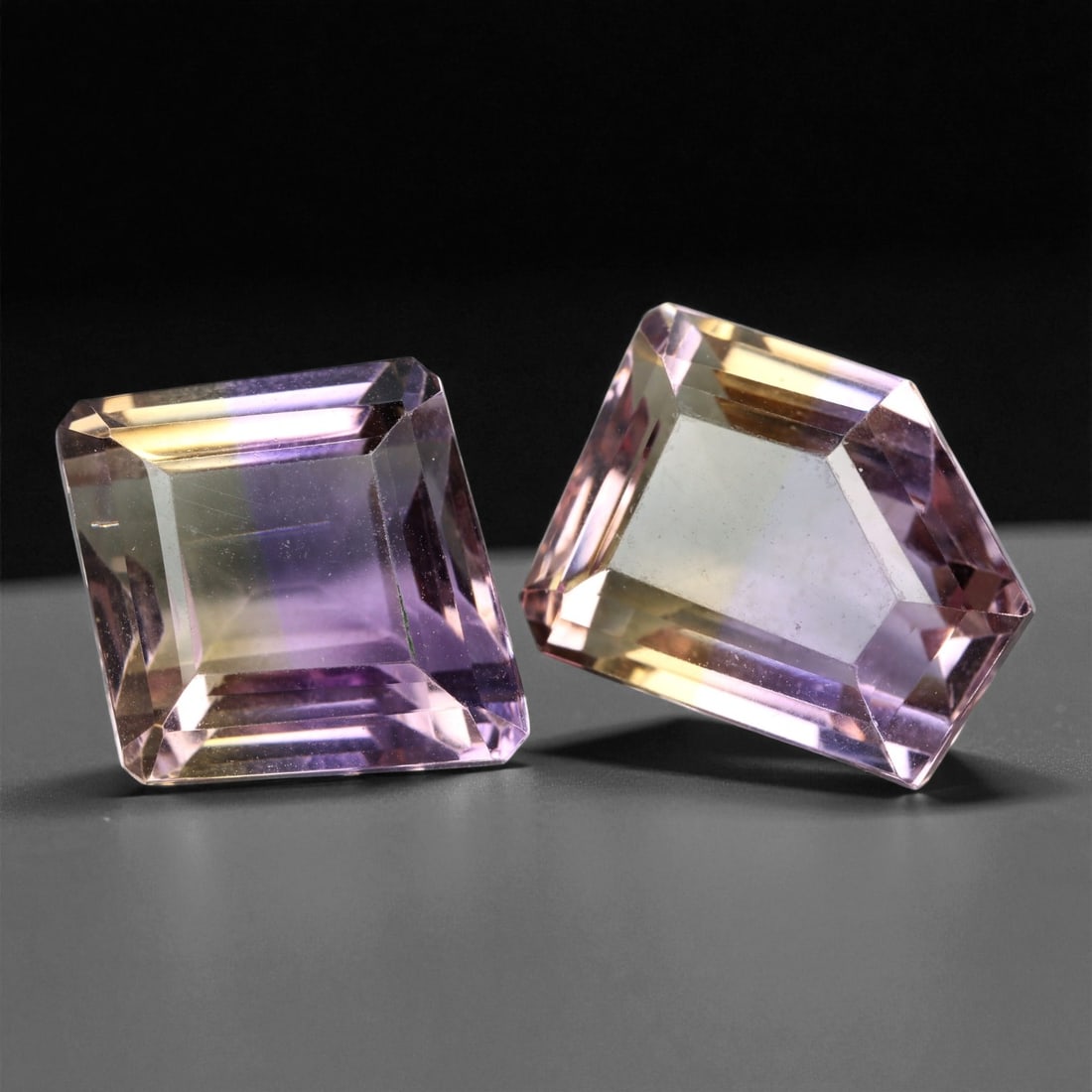 30.85 Carats Bi-Color Purple and Golden Ametrine Pair - Natural Bolivian Stones, 1.8x1.6cm, 85XE: This captivating pair of ametrines showcases a mesmerizing union of lavender-purple and golden hues, masterfully fused within each gem. Their precision step cuts enhance the dramatic contrast of color
