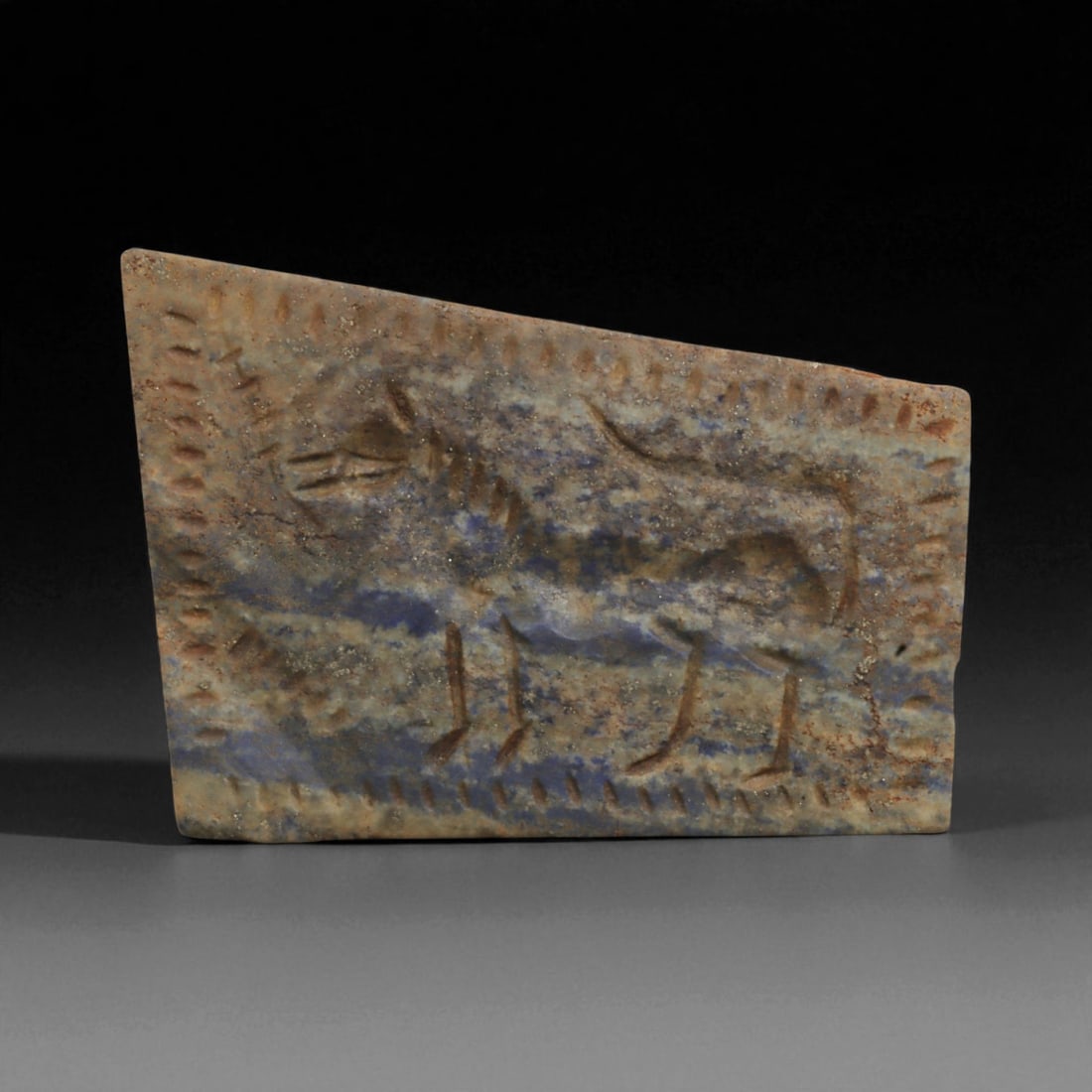 A Neo-Assyrian Lapis Lazuli Plaque with Leaping Horse Relief, c. 8th-7th Century BCE, 7.3cm, 91BQ: This finely carved lapis lazuli plaque originates from the Neo-Assyrian Empire, which dominated Mesopotamia from 911 to 609 BCE. The Assyrians were masters of monumental art and miniature glyptic trad