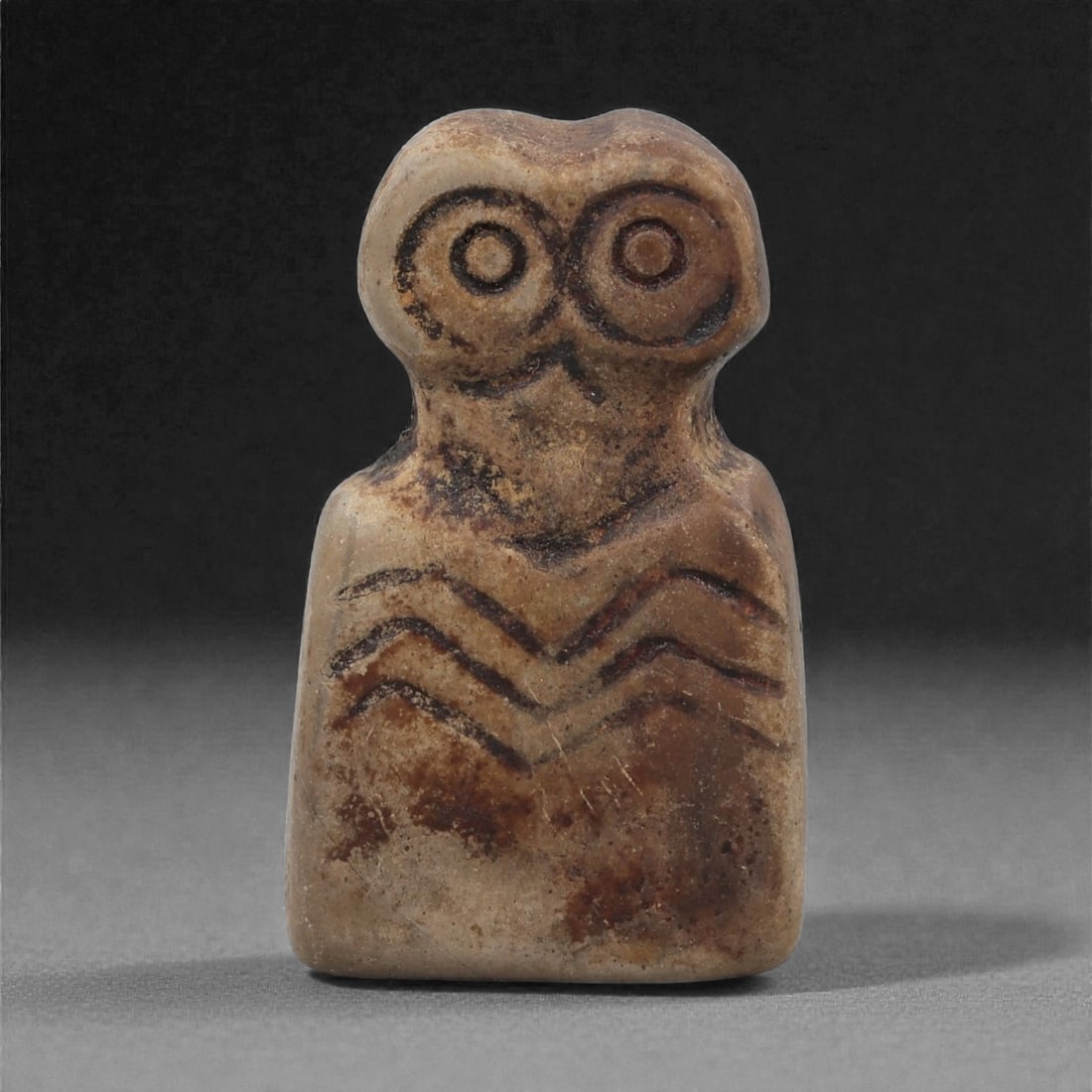 A Near Eastern Stone Eye Idol, 4th-3rd Millennium BCE, 56LH: Carved from a light to medium brown stone with areas of surface accretion, the figure is shaped with a squared lower body and a narrower upper section bearing two large circular eyes formed by recesse