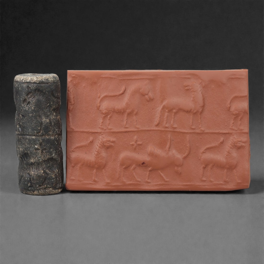 A Near Eastern Stone Cylinder Seal, 3rd Millennium BCE, 4.9cm, 15LH: Carved from stone with darker surface mottling, the cylindrical seal bears a continuous engraved scene. The carving is executed in shallow linear grooves typical of Early Bronze Age glyptic traditions