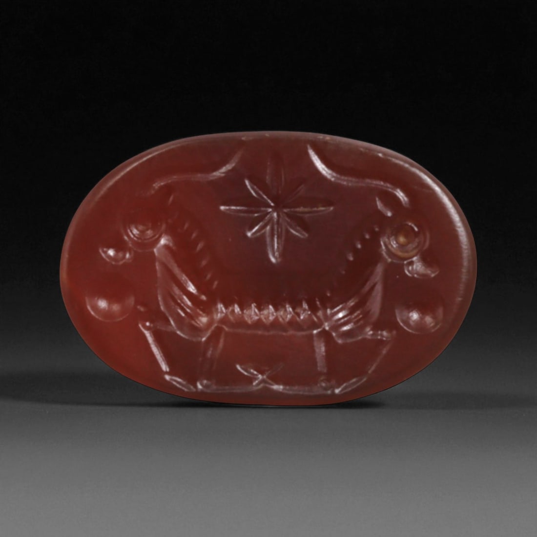 Ancient Sasanian Solar Symbol and Ram Intaglio in Carnelian, c. 3rd-6th Century CE, 2cm, 98BV: This exquisite oval carnelian intaglio originates from the Sasanian Empire, the last pre-Islamic dynasty of Persia (224-651 CE), renowned for its sophisticated lapidary artistry and symbolic imagery. 