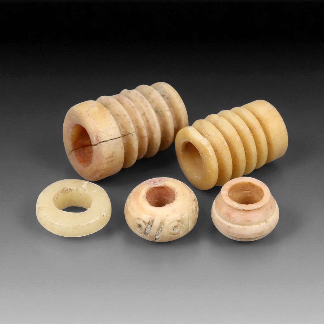 Ancient Mesopotamian Grooved Bone Spindle Whorl Set, c. 2000-1600 BCE, 0.5-1.5cm, 3g, 20LH: This compelling set of four ribbed bone spindle whorls hails from the heart of ancient Mesopotamia, where textile production was both a domestic necessity and a cornerstone of temple economies. Dated 
