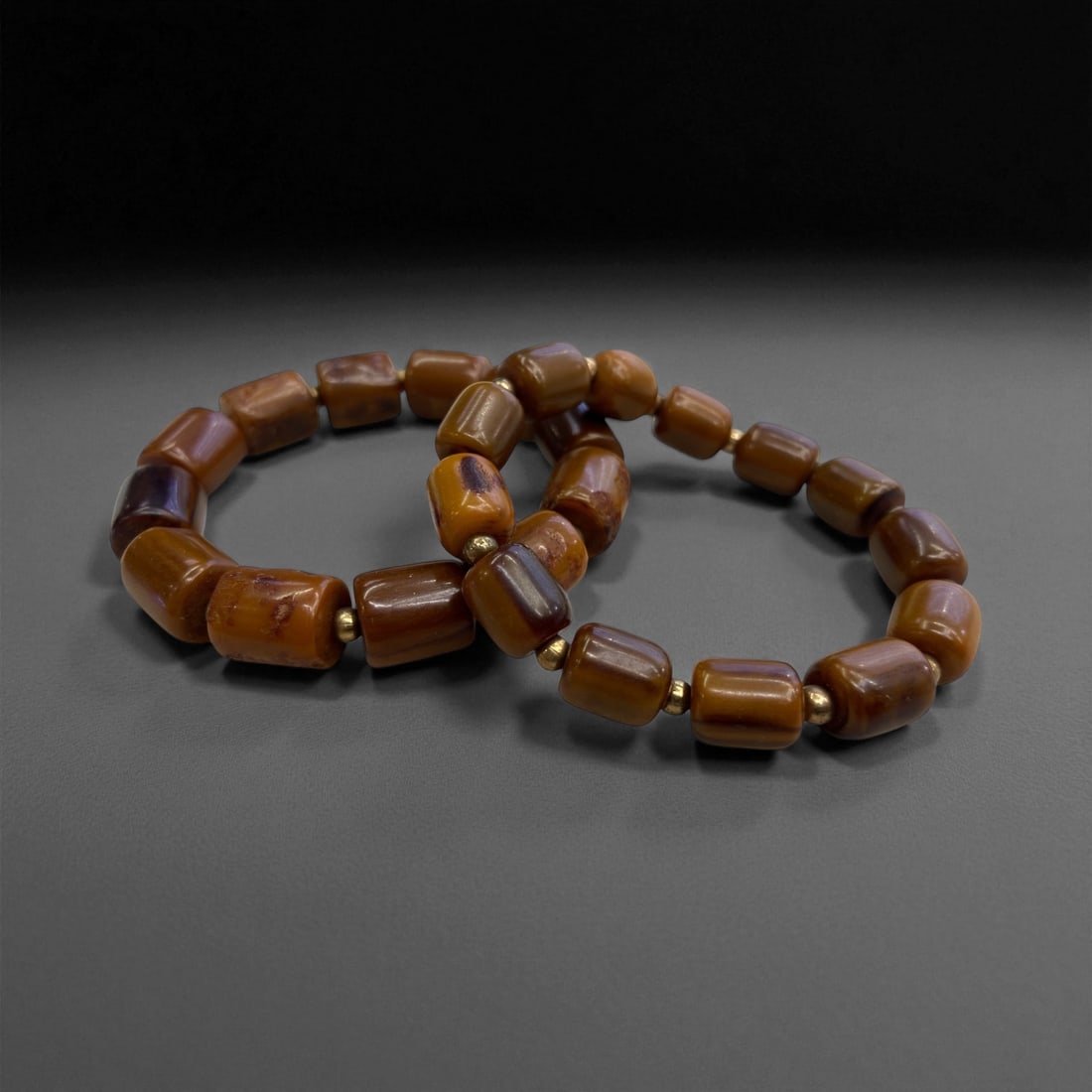 A Pair of Amber Bead Bracelets, Mid-20th Century, 33g, 46EE: Comprising two bracelets strung with cylindrical amber beads in warm brown and honey tones, each bead shows natural internal clouding and surface variation typical of fossil resin. Small metal spacer