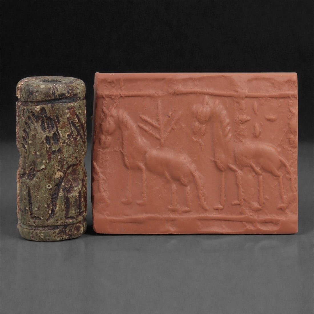 A Near Eastern Stone Cylinder Seal, 3rd Millennium BCE, 4cm, 31LM: Carved from stone with darker surface mottling, the cylindrical seal bears a continuous engraved scene. The carving is executed in shallow linear grooves typical of Early Bronze Age glyptic traditions