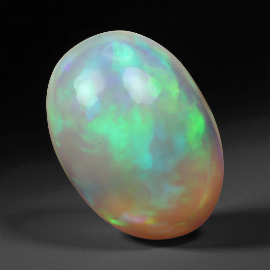 4.65 Carats Pastel Neon Welo Opal Cabochon - Natural Ethiopian Gemstone, 16XE: This glowing Welo opal shimmers with delicate flashes of mint green, lavender, sky blue, and soft amber beneath a translucent, honey-toned body. Its internal light play is gentle yet vivid, with broad