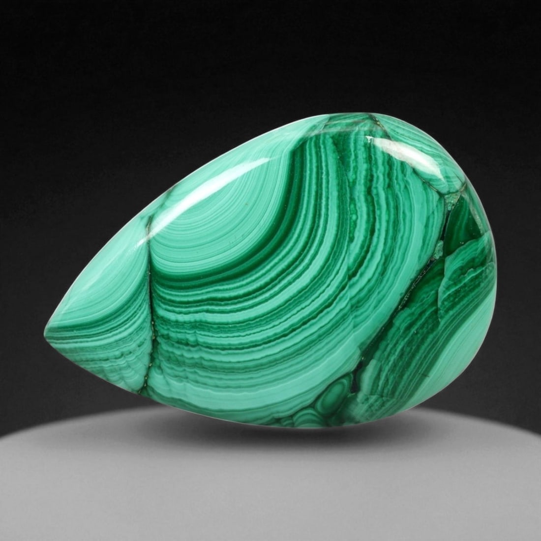 63.19 Carats Banded Forest Green Malachite Pear Cabochon - Natural Congolese Stone, 62WE: This exceptional 63.19-carat malachite cabochon showcases mesmerizing concentric banding in vivid forest and mint green tones. The rhythmic circular patterns flow gracefully across its polished pear s