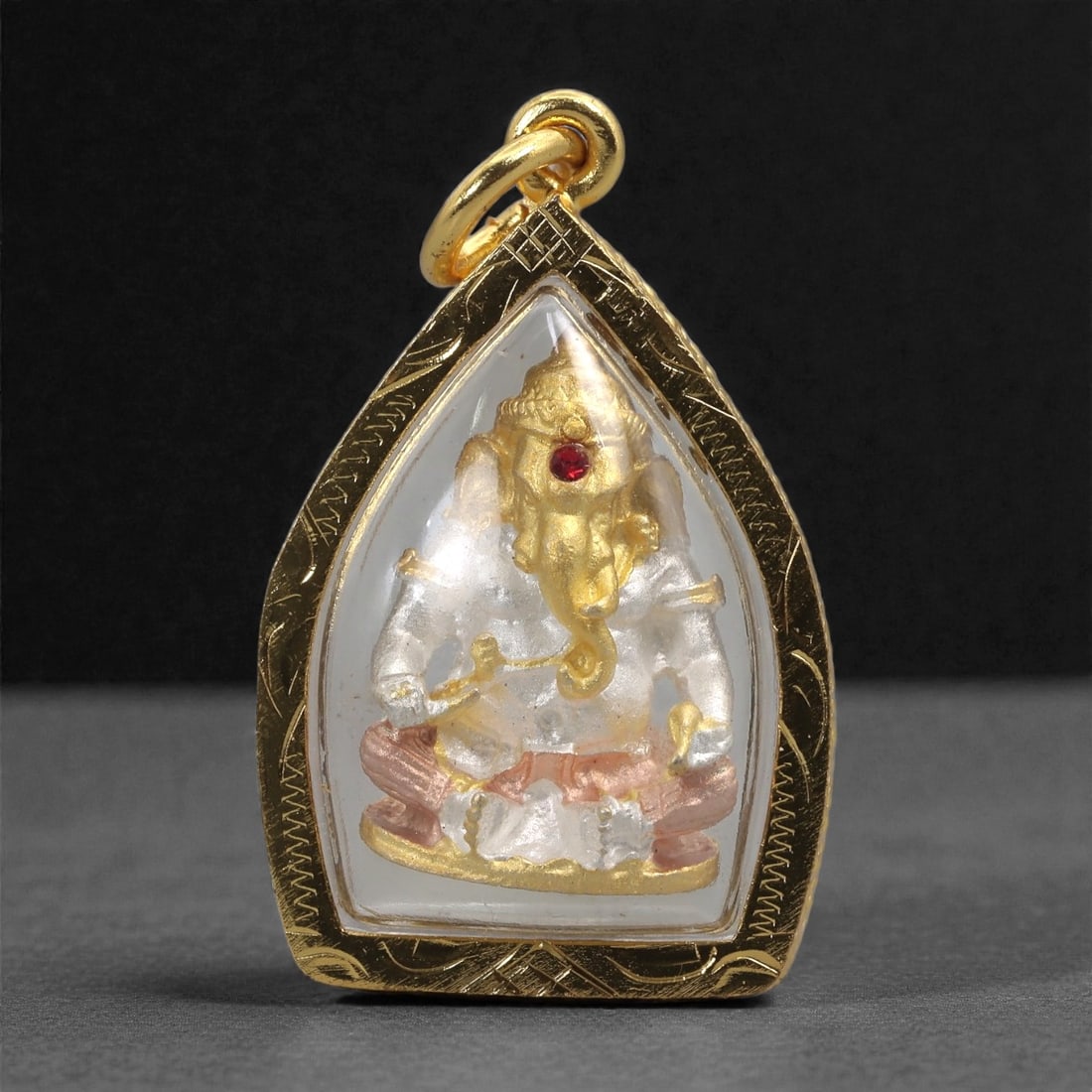 Hindu Painted Metal Amulet - Ganesha Figurine Pendant, 100C: This pendant contains a molded metal depiction of Ganesha, rendered in gilt and silvered tones with a small red inlay marking the forehead. The deity is shown seated with clearly defined limbs and att