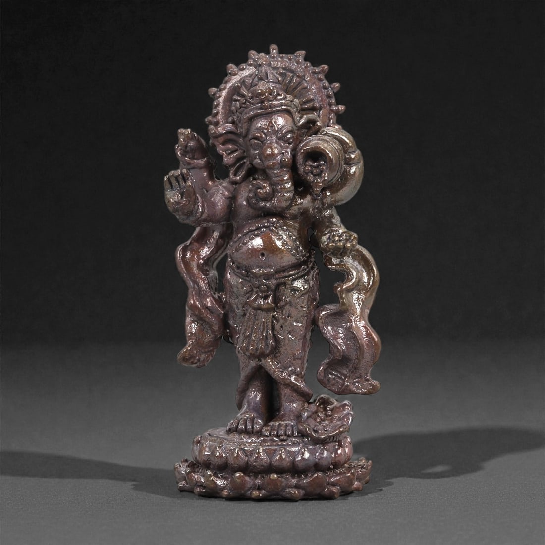 Bronze Ganesha Idol - Hindu Figurine, 15D: Cast in bronze with a smoothly finished surface, this small figurine depicts the elephant-headed deity Ganesha in a lively and expressive stance. The rounded belly, curling trunk, and flowing sash ele