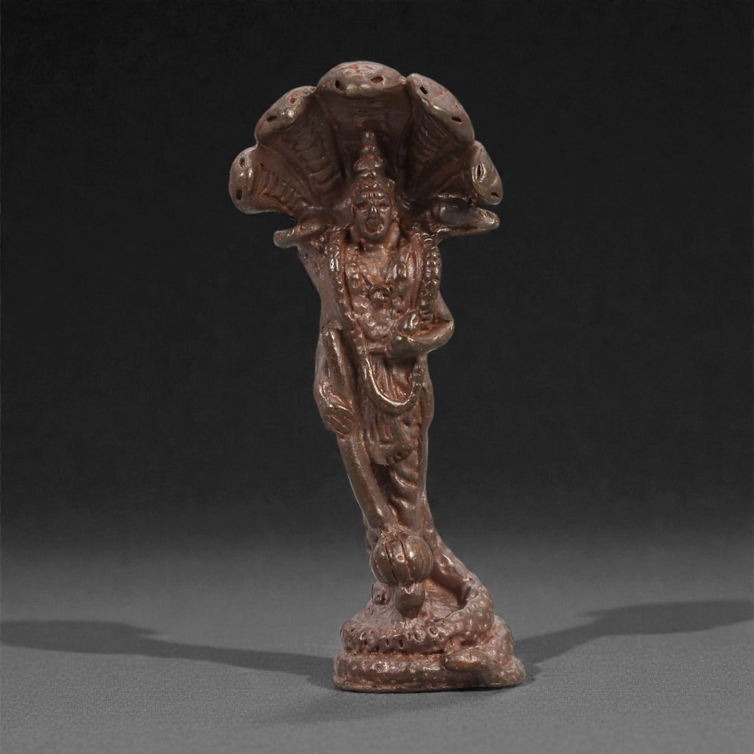 Bronze Serpent-Hood Deity - Hindu Naga Icon Figurine, 9D: Cast in bronze with a smooth, gently reflective surface, this slender figurine depicts a standing deity sheltered beneath the expanded hood of a multi-headed serpent. The figure is shown in an elegant