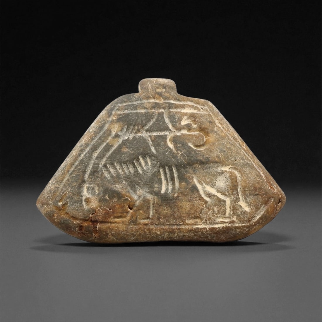 A Proto-Elamite Hero and Ibex Motif Steatite Pendant Plaque, c. 30th-27th Century BCE, 4.9cm, 98ET: This finely carved steatite pendant plaque from the Proto-Elamite period of southwestern Iran presents one of the earliest known visual expressions of divine struggle and human mastery over nature. Th