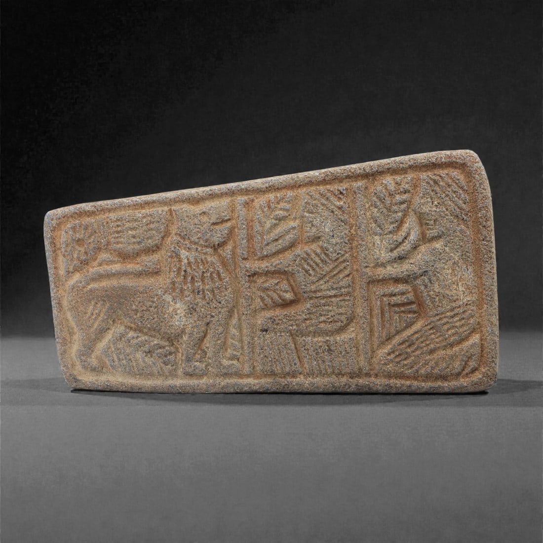 A Sasanian Lapis Lazuli Relief Plaque, 3rd-7th Century CE, 9.5cm, 86LR: Carved from lapis lazuli with brown archaeological surface accretions, the plaque is worked in shallow relief exhibiting the characteristic linear incision and patterned surface treatment associated w