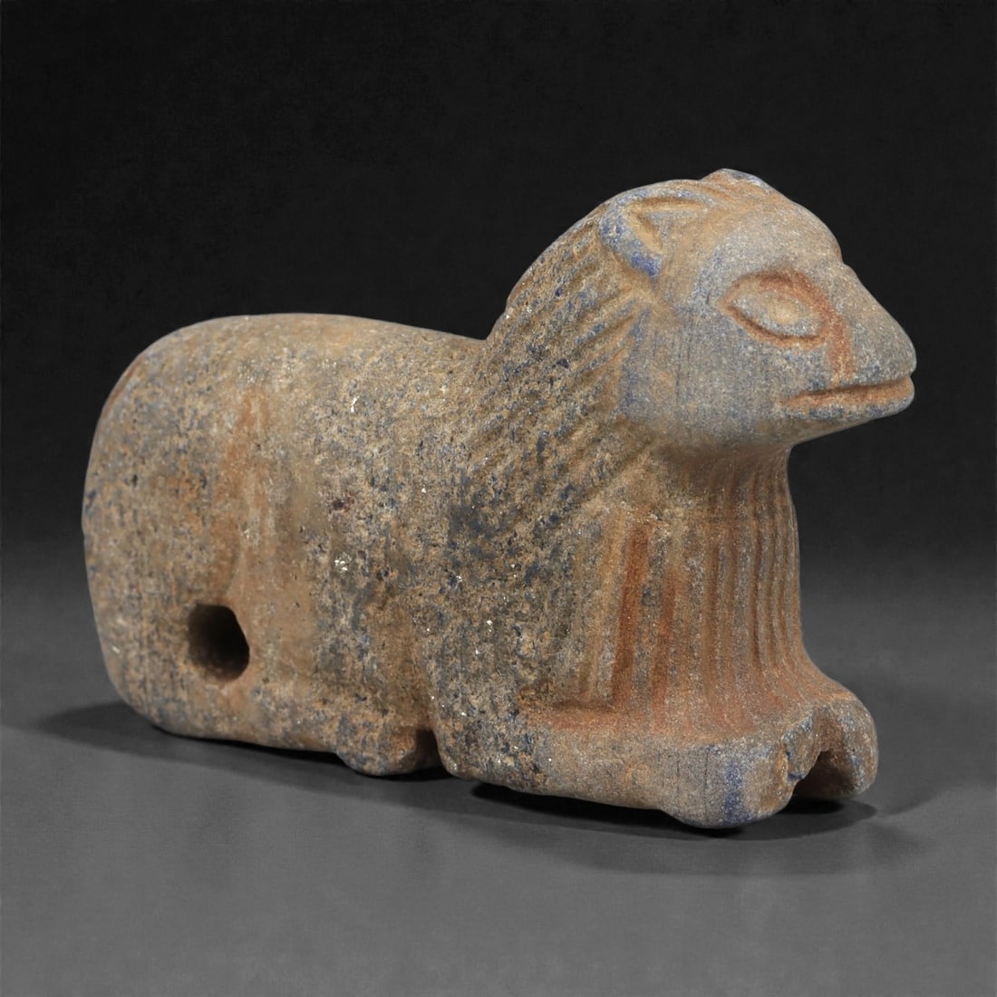 A Parthian Lapis Lazuli Feline Effigy Amulet, 1st Century BCE-2nd Century CE, 56LR: Carved from lapis lazuli with brown archaeological surface accretions, the amulet takes the form of a recumbent feline rendered with a compact body, short legs, and a prominent head set forward from t