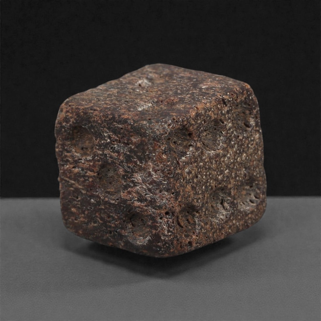 A Roman Bone Gaming Die, 1st-3rd Century CE, 1.2cm, 83AD: Carved from dense bone, the object is shaped as a small cube with slightly rounded edges. Each face bears a series of drilled circular pips arranged in standard numerical configurations. The surfaces 