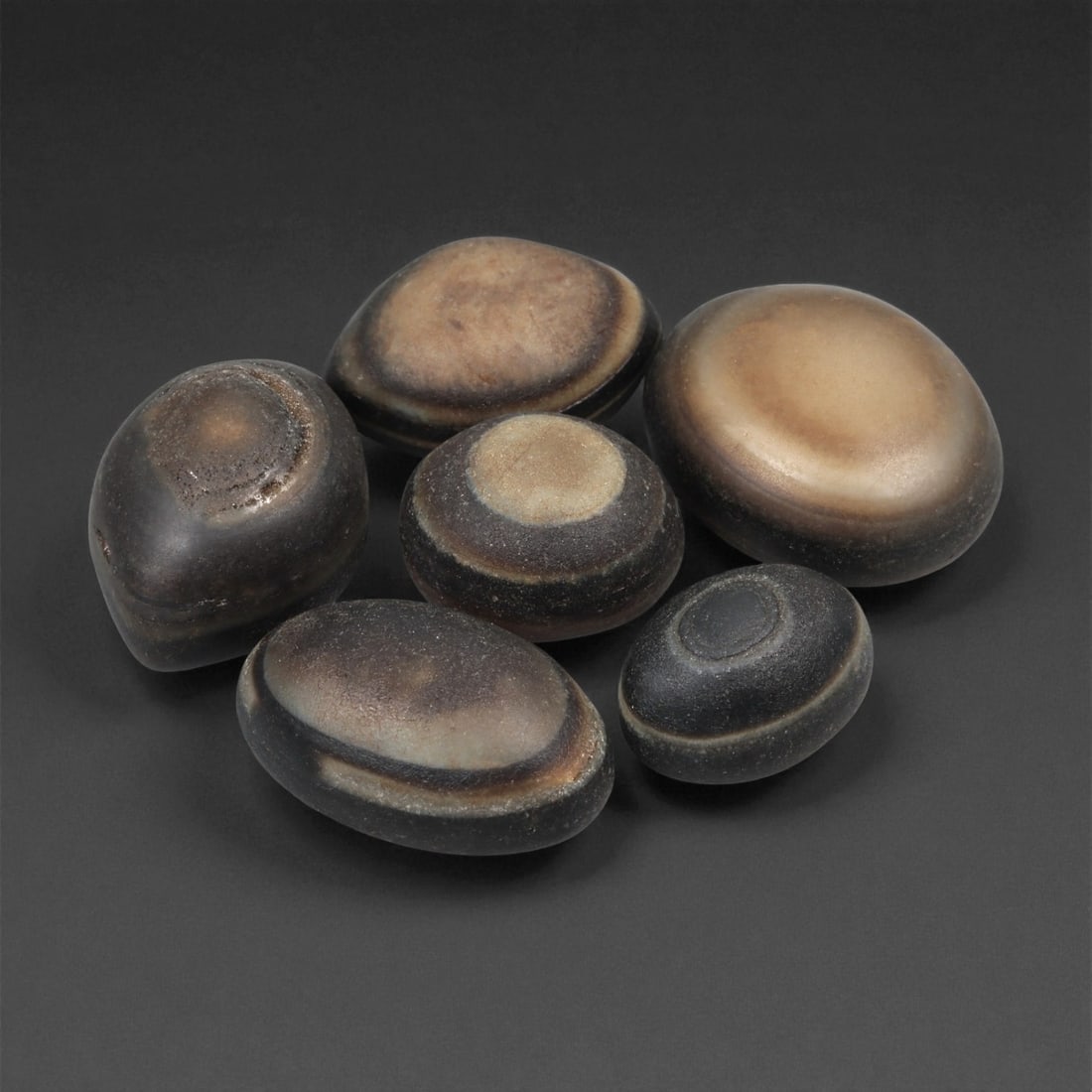 A Group of Tibetan Stone Luk Mik ("Goat Eye") Beads, 19th-Early 20th Century, 26LG: Carved from banded agate and chalcedony, the group comprises six domed, oval, and lenticular beads characterized by concentric circular banding that creates the "eye" motif associated with luk mik for