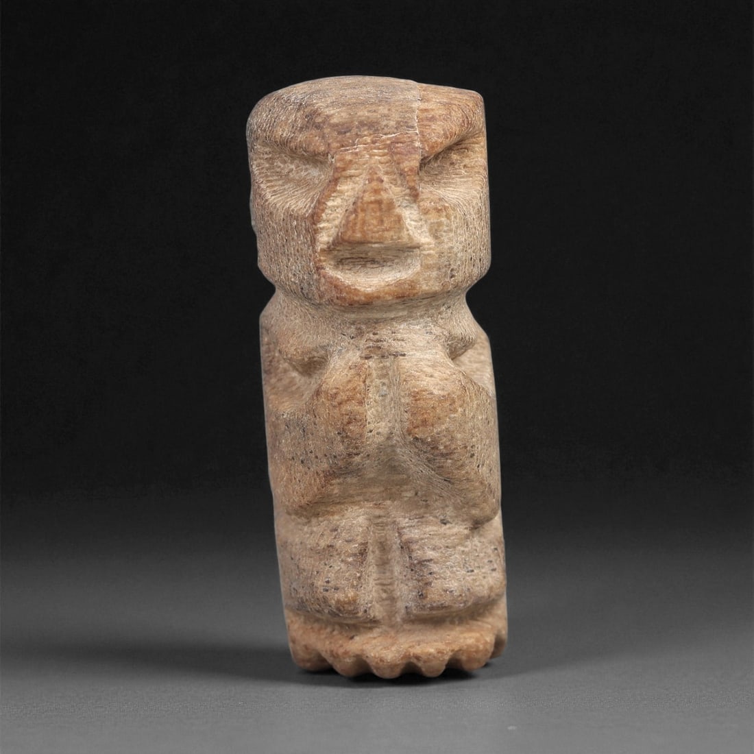 A Taino Carved Stone Idol, Late Ceramic Age, circa 1200-1500 CE, 78LD: Carved from a light brown stone with a fine granular texture, the figure is shown standing with a narrow, elongated body and short legs. The head is rectangular with recessed horizontal eyes, an incis
