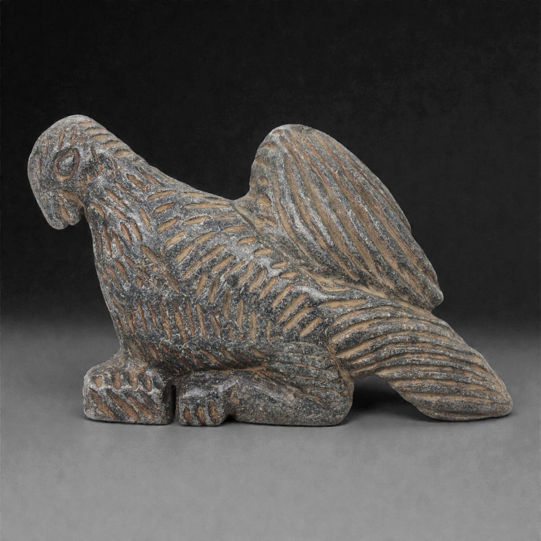 A Syro-Anatolian Schist Bird Figure, Iron Age, 1st Millennium BCE, 53LK: Carved from dark grey schist, the figure depicts a large bird shown in a crouched posture with the legs positioned beneath the body and the wings raised slightly along the back. The head is rendered w