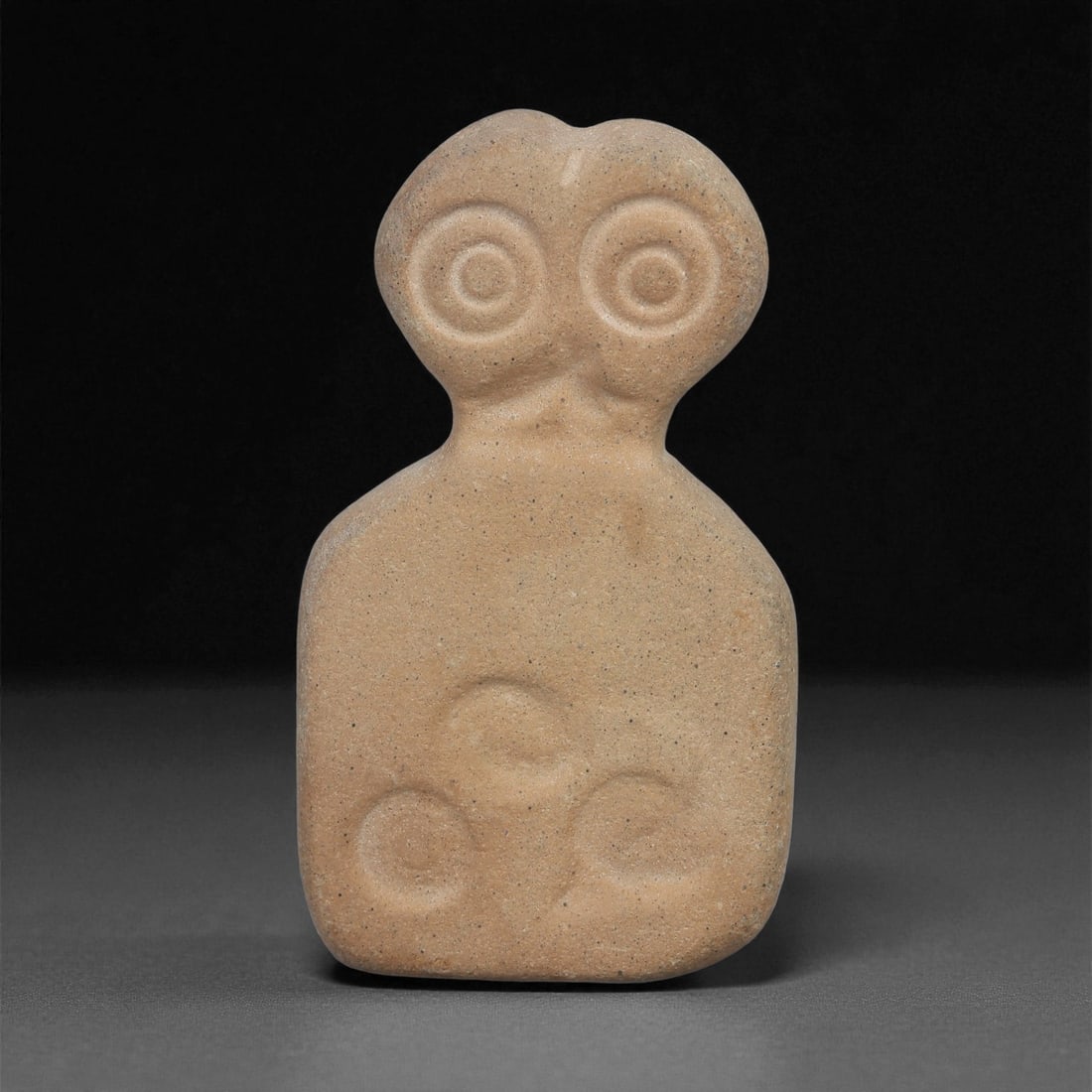 A Near Eastern Stone Eye Idol, 4th-3rd Millennium BCE, 6LB: Carved from a light brown stone with a smooth, even surface, the object is shaped with a broad tapering body, a narrow neck, and a bifurcated upper section. The head bears a pair of recessed circular