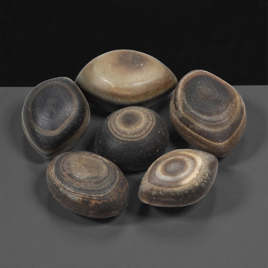 A Group of Tibetan Stone Luk Mik ("Goat Eye") Beads, 19th-Early 20th Century, 28LG: Carved from banded agate and chalcedony, the group comprises six domed, oval, and lenticular beads characterized by concentric circular banding that creates the "eye" motif associated with luk mik for