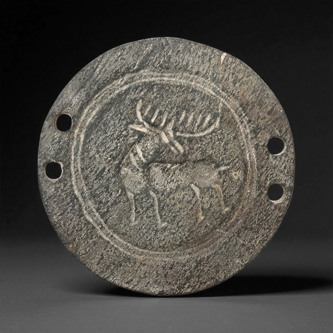 Ancient Elamite Horned Stag Steatite Round Plaque, c. 25th-23rd Century BCE, 7.6cm, 35ES: This circular steatite plaque, carved during the Elamite period of southwestern Iran, captures the timeless symbolism of the stag-a sacred emblem of vitality, renewal, and divine guardianship. The com