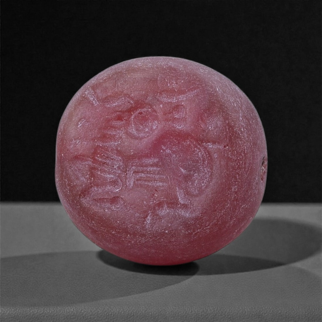 A Near Eastern Red Stone Intaglio with Stylised Quadruped, 1st Millennium BCE, 95J: Carved from an opaque red stone, the circular intaglio bears a shallowly engraved image of a quadruped shown in profile, rendered with schematic linear detailing for the head, limbs, and body. Additio