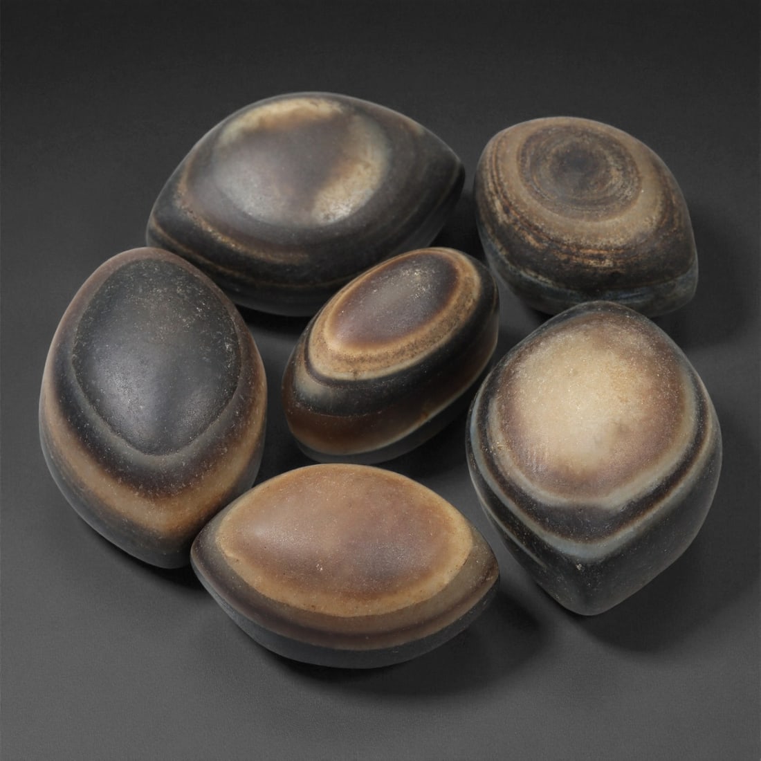 A Group of Tibetan Stone Luk Mik ("Goat Eye") Beads, 19th-Early 20th Century, 13LG: Carved from banded agate and chalcedony, the group comprises six domed, oval, and lenticular beads characterized by concentric circular banding that creates the "eye" motif associated with luk mik for
