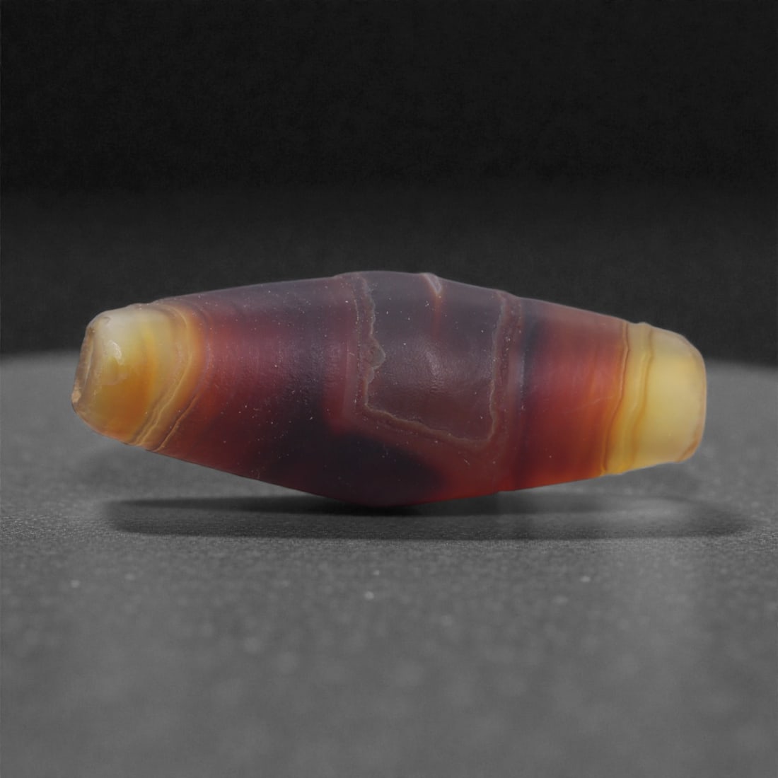 Antique Agate Bead - Himalayan Chung Dzi Amulet, 2.7cm, 64X: The bead is carved from banded agate, carefully shaped into a short cylindrical form with gently rounded ends and a central perforation. The stone displays a natural contrast between a pale central zo