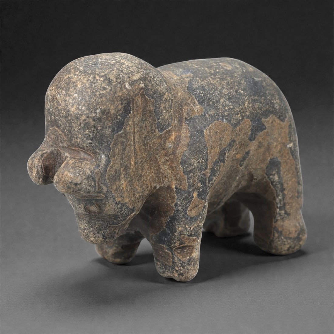 A Near Eastern Stone Zoomorphic Effigy, 3rd-2nd Millennium BCE, 70LE: Carved from a dark mottled stone with lighter surface patches, the object represents a quadruped standing on four short legs. The head is rounded with a short projecting snout, and the body is compact