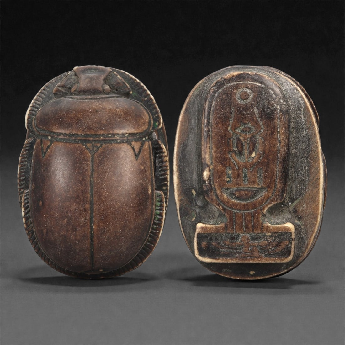 An Egyptian Inscribed Steatite Scarab, New Kingdom, c. 1550-1180 BCE, 94LN: Carved from dark brown steatite with traces of green surface pigment, the scarab is shaped with a smooth ovoid back, delineated wing cases, and carefully incised legs and thorax. The underside bears a