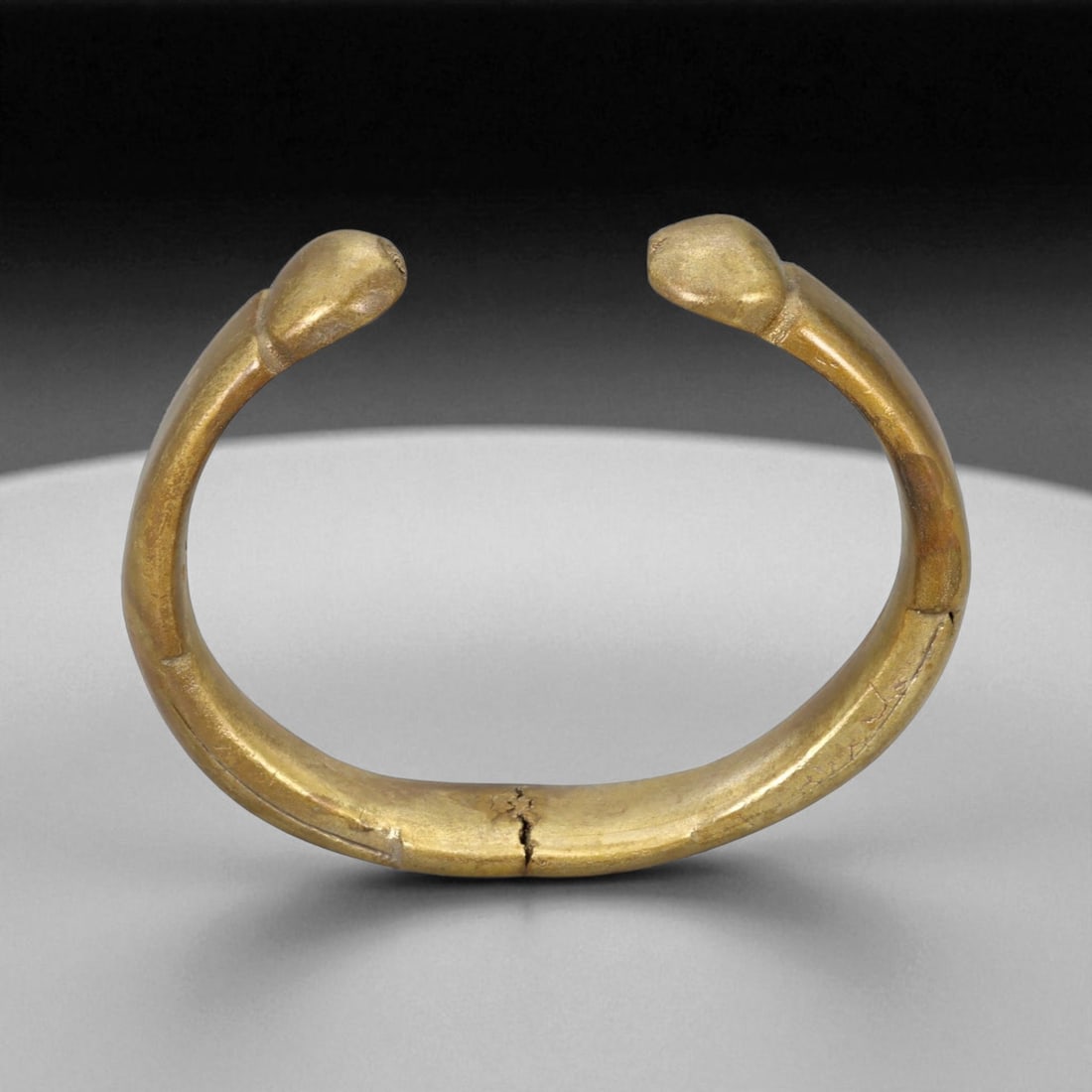 A West African Royal Manilla Currency Bracelet Symbolic Bronze Form, 19th Century, 7.5cm, 121g, 30Q: This powerful A currency bracelet, known as a manilla, originates from West Africa and dates to the 19th century. Heavy, closed-ended forms like this were often used not only in trade but also as symb