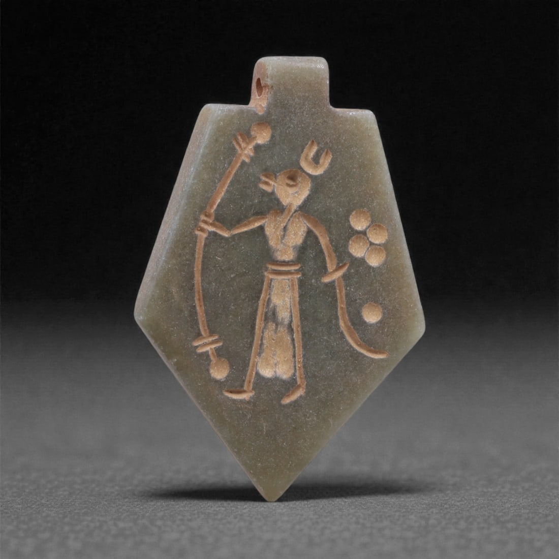 An Eastern Iranian Serpentine Amulet, Islamic Period, 9th-10th Century CE, 4.2cm, 95K: Carved from pale green serpentine with a smooth, slightly translucent surface, the object is worked in low relief on one face, with the reverse left plain and undecorated. The carved elements are defi