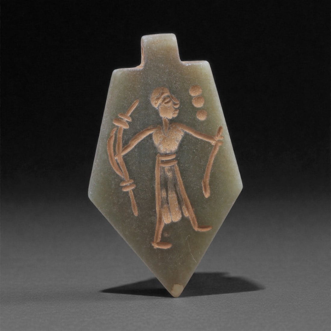 An Eastern Iranian Serpentine Amulet, Islamic Period, 9th-10th Century CE, 4.4cm, 20K: Carved from pale green serpentine with a smooth, slightly translucent surface, the object is worked in low relief on one face, with the reverse left plain and undecorated. The carved elements are defi