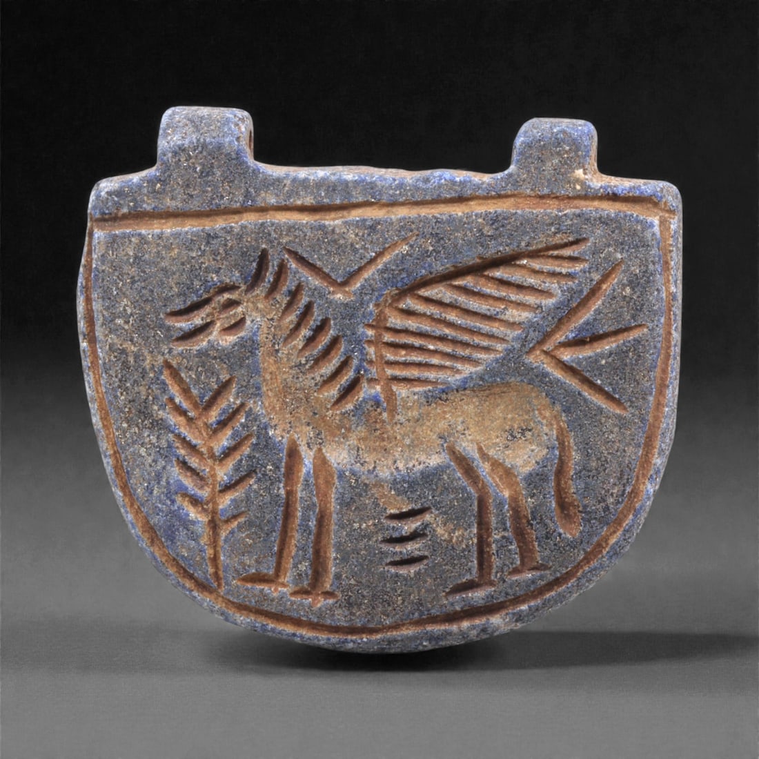 A Sasanian Lapis Lazuli Amulet, 3rd-7th Century CE, 4cm, 25Q: Carved from deep blue lapis lazuli with visible lighter inclusions and natural granular texture, the object is finished with a flat reverse and a front surface worked in low relief. The carving is exe