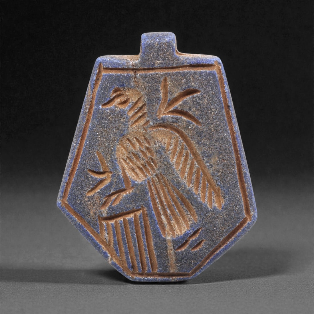 A Sasanian Lapis Lazuli Amulet, 3rd-7th Century CE, 4.3cm, 24Q: Carved from deep blue lapis lazuli with visible lighter inclusions and natural granular texture, the object is finished with a flat reverse and a front surface worked in low relief. The carving is exe