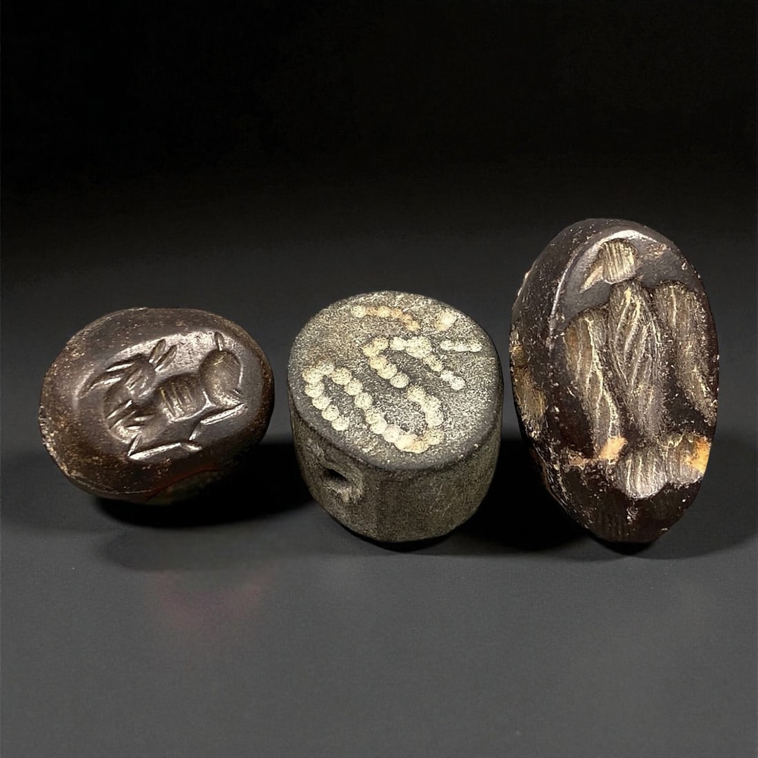 Ancient Neo-Assyrian Hematite and Schist Stamp Seal Group, c. 9th-7th Century BCE, 1.2-1.7cm, 90EP: This refined group of three stamp seals, carved from hematite and schist, represents the enduring artistry of the Neo-Assyrian period - an age when glyptic art served both bureaucratic and sacred func