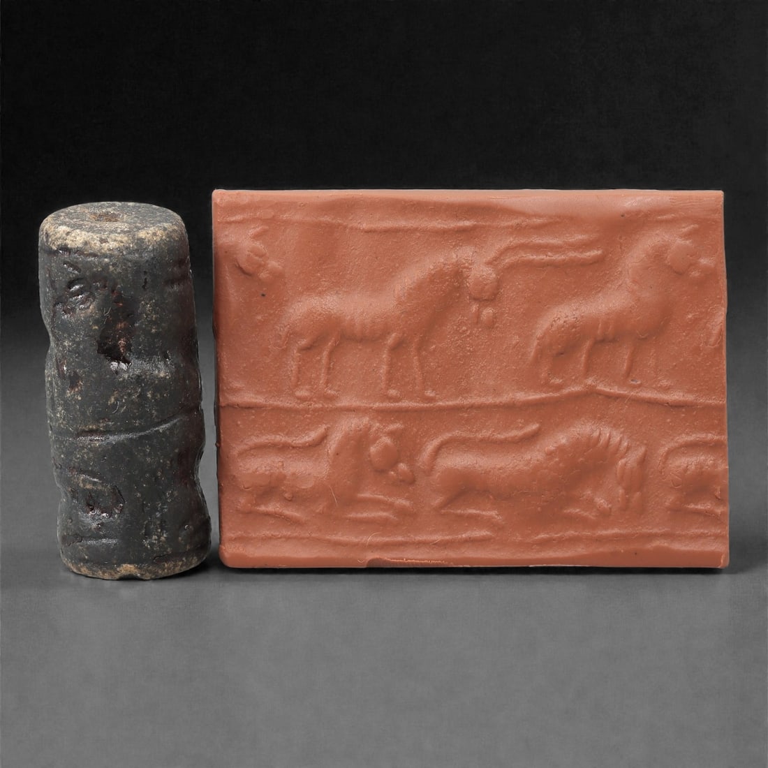 A Near Eastern Stone Cylinder Seal, 3rd Millennium BCE, 4.2cm, 44LJ: Carved from stone with darker surface mottling, the cylindrical seal bears a continuous engraved scene. The carving is executed in shallow linear grooves typical of Early Bronze Age glyptic traditions