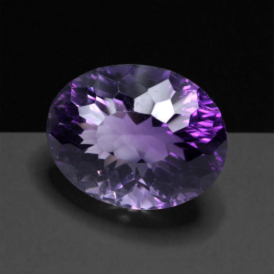 17.47 Carats Lavender Purple Amethyst Oval - Natural Brazilian Gem, Concave Cut, 81XB: This dazzling amethyst showcases an exquisite lavender-purple tone with luminous depth, enhanced by a masterfully executed concave cut. Measuring 18 x 14.2 x 12.1 mm, the gem exhibits an elevated play