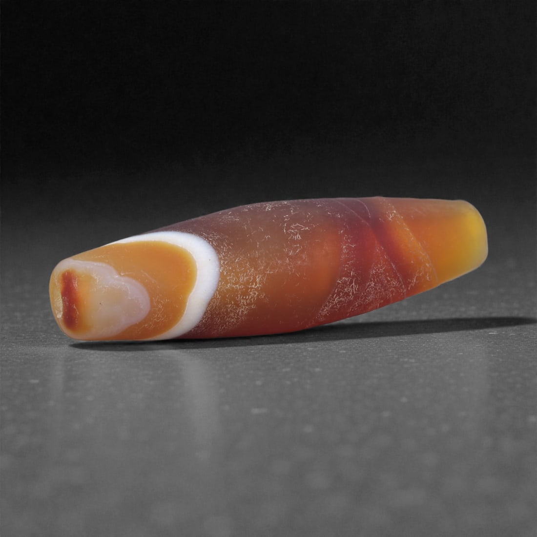 Antique Agate Bead - Himalayan Chung Dzi Amulet, 3.4cm, 77X: The bead is carved from banded agate, carefully shaped into a short cylindrical form with gently rounded ends and a central perforation. The stone displays a natural contrast between a pale central zo