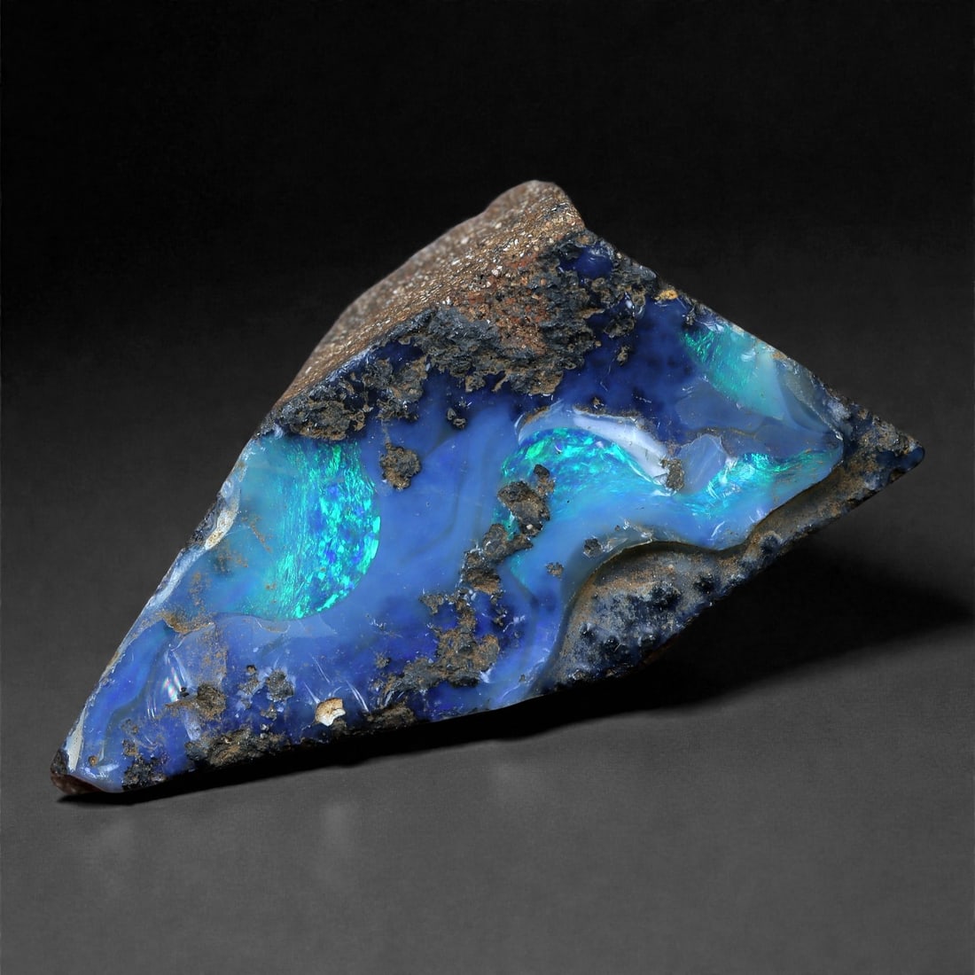 20.92 Carats Deep Blue-Green Boulder Opal Rough - Natural Winton, Australia, 42XC: This vibrant 24 x 17 mm boulder opal rough features an electric combination of cobalt blue and neon green fire, flashing through swirling bands of translucent opal embedded in earthy ironstone. Natura