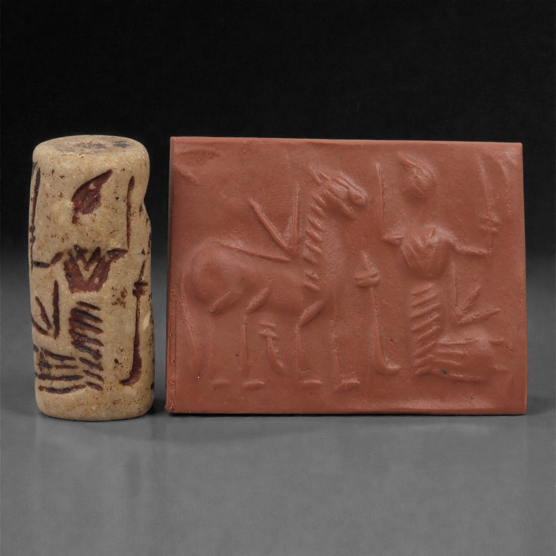 A Near Eastern Stone Cylinder Seal, 3rd Millennium BCE, 3.5cm, 5LP: Carved from stone with darker surface mottling, the cylindrical seal bears a continuous engraved scene. The carving is executed in shallow linear grooves typical of Early Bronze Age glyptic traditions